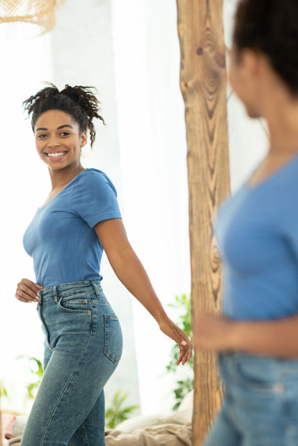 woman looking in mirror wearing blue shirt
