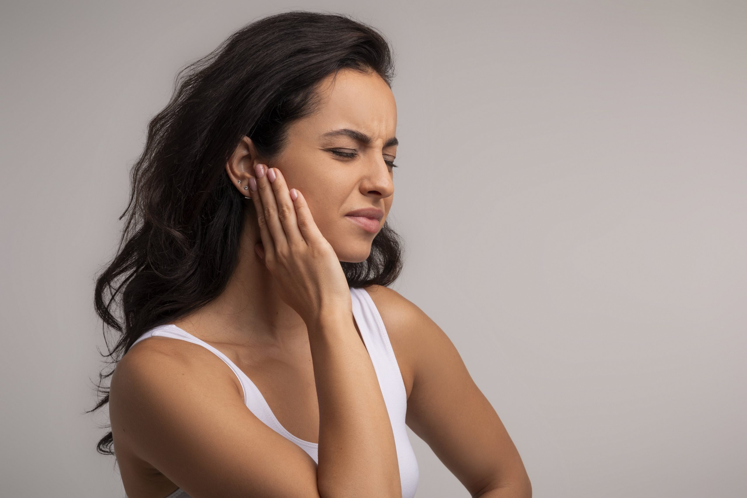 woman with TMJ pain touching her painful jaw